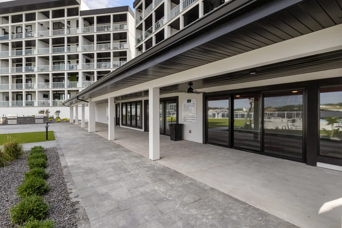 This image captures the modern architecture of the property, landscaped pathways, and large glass windows that invite the outdoors in. Guests are shown relaxing outdoors, enjoying gatherings, and taking in sunset views from the patio.