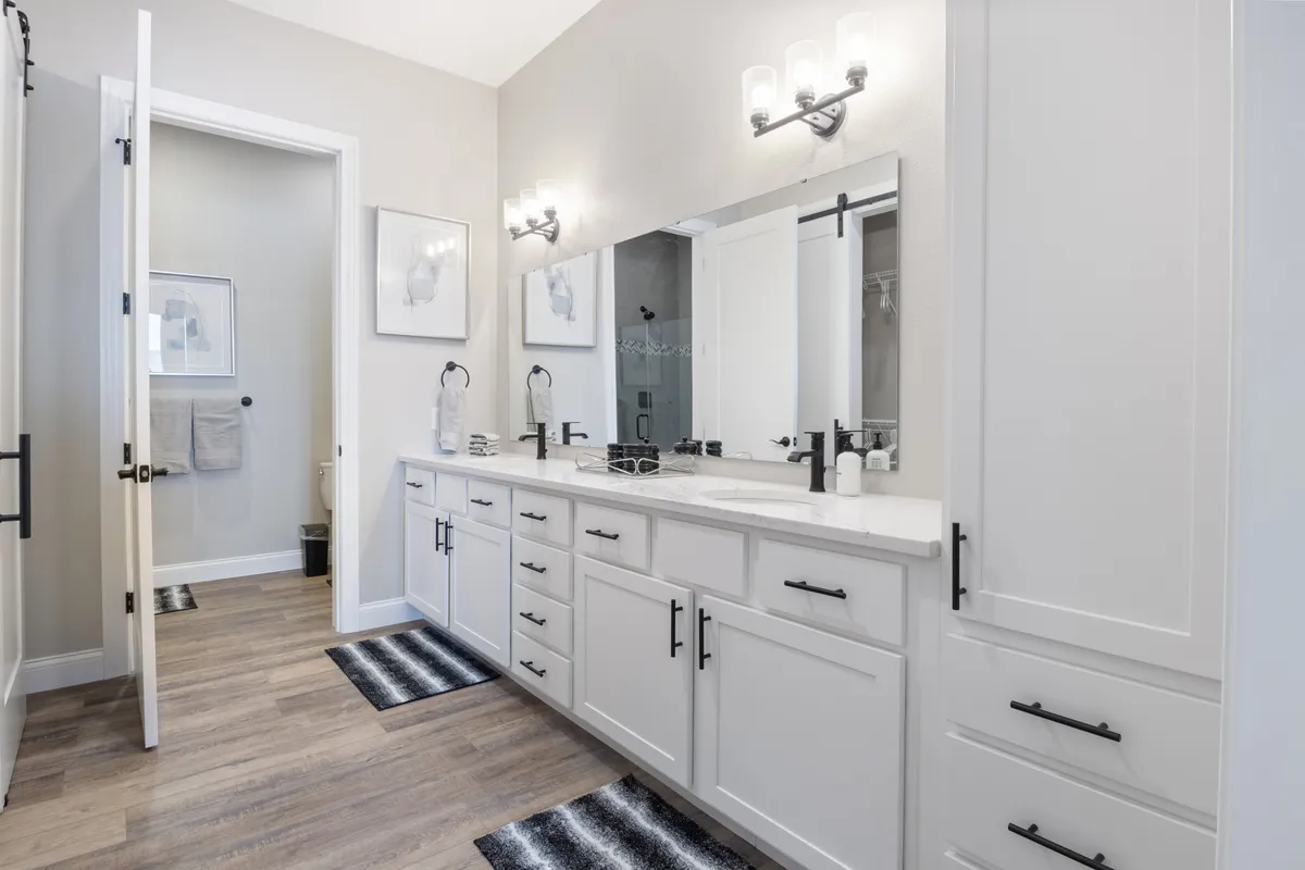 A serene ensuite bathroom with a double vanity, large mirrors, and modern fixtures. The space is bright and inviting, perfect for morning routines or relaxing after a day outdoors.